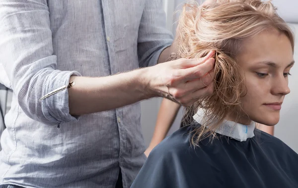 Een kapper maken een kapsel voor een blonde vrouwelijke client — Stockfoto