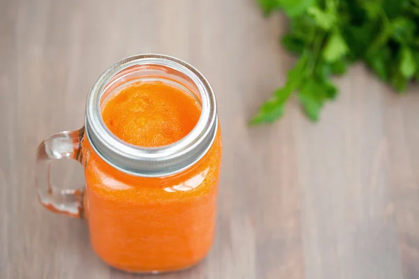 Gesunder Karotten-Smoothie im Glas mit Röhrchen auf Holzgrund — Stockfoto