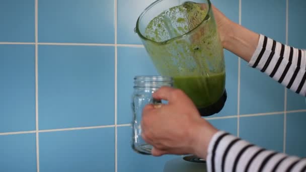 Poring πράσινο υγιεινό smoothie από μια γυάλινη κανάτα του μπλέντερ σε ένα βάζο κτιστών — Αρχείο Βίντεο