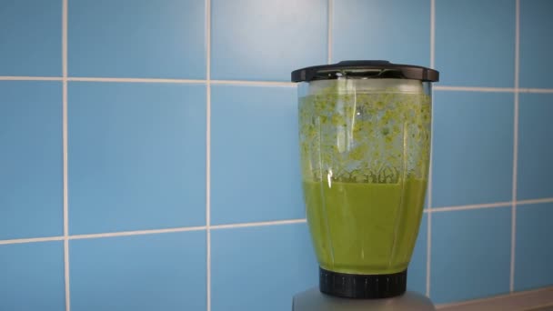 Een blenderkan met groene gezonde smoothie op blauw — Stockvideo