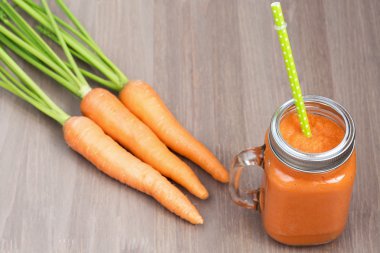 Sağlıklı havuç güler yüzlü bir kavanoza tüp ahşap arka plan