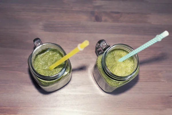 两个绿色果汁在罐子里，用管 — 图库照片