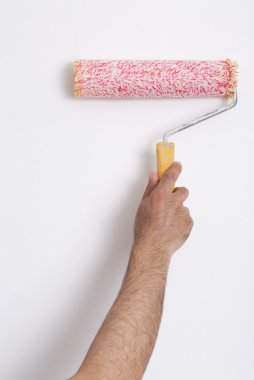Kırmızı boya silindiri ile bir duvar boyama ressam kolu yakın çekim