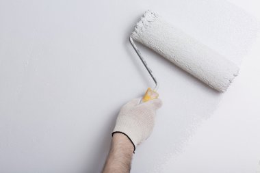 Bir duvar boya silindiri ile boyama ressam kolu yakın çekim