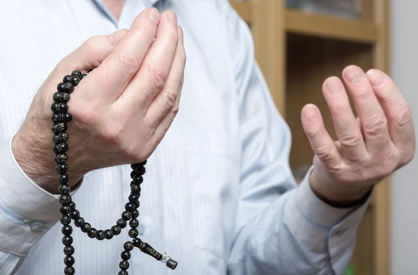 Biddende handen van een oude man met rozenkrans kralen — Stockfoto