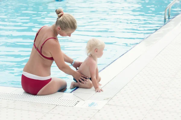 Rubia madre y su pequeño hijo junto a una piscina — Foto de Stock