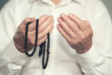 Tespih tutan bir yaşlı adamın dua eden eller