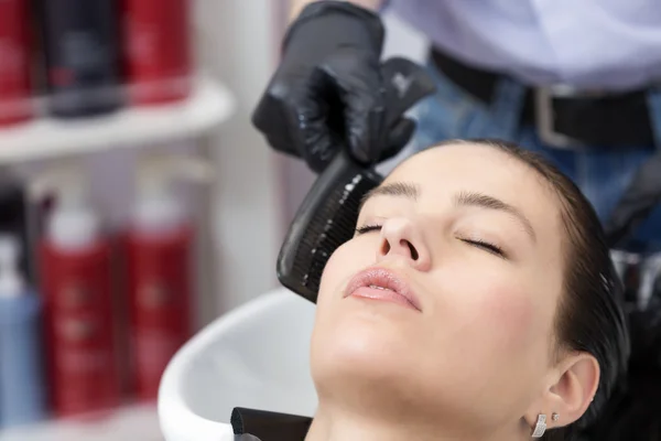 Une femme brune lave les cheveux dans un studio de coiffure — Photo