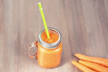 Sağlıklı havuç güler yüzlü bir mason kavanoza ahşap arka plan üzerinde çiğ havuç