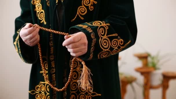 Старый мулла в национальной одежде молится с четками в руках — стоковое видео