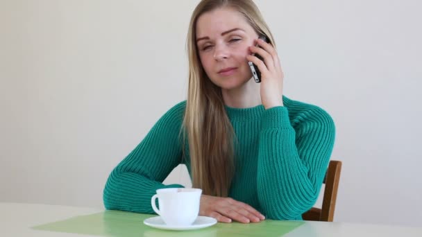 Hermosa mujer rubia bebiendo café y hablando por teléfono — Vídeos de Stock