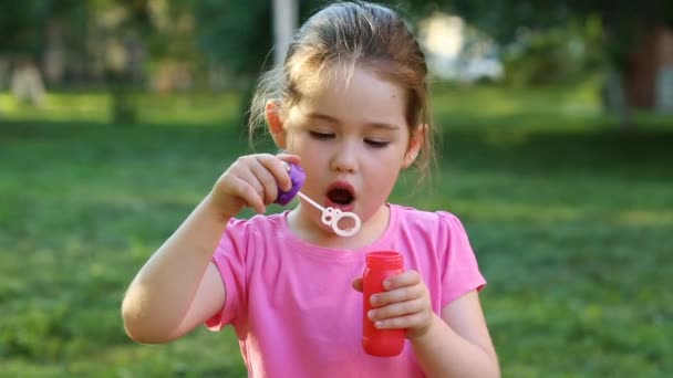 Gelukkig kind blazen van zeepbellen in park — Stockvideo