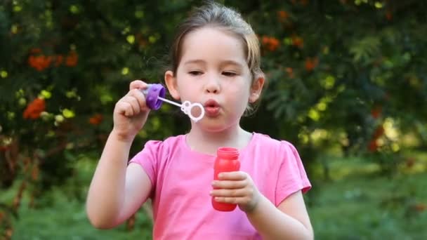 Happy child blowing soap bubbles in park — Stock Video