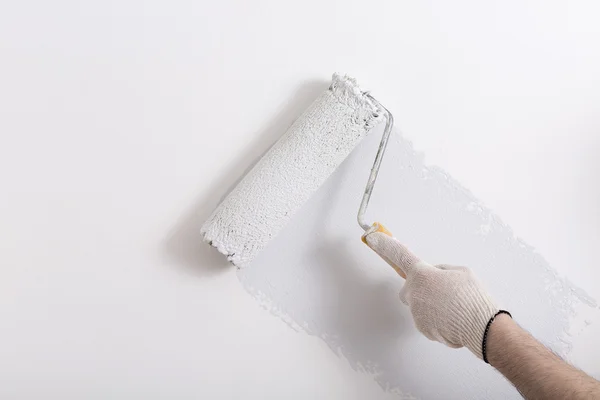 Gros plan du bras du peintre peignant un mur avec rouleau de peinture — Photo