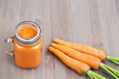 Sağlıklı havuç güler yüzlü bir mason kavanoza ahşap arka plan üzerinde çiğ havuç