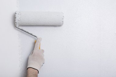 Bir duvar boya silindiri ile boyama ressam kolu yakın çekim