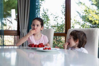 Evde taze olgun çilek yiyen tatlı çocuklar.