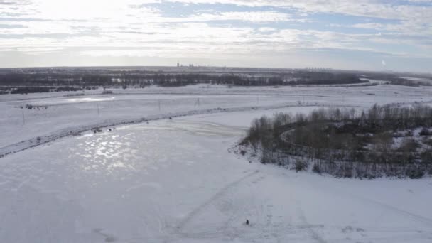 Um pescador que pesca no inverno no rio coberto de gelo — Vídeo de Stock