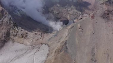 İnsanlar fümerollü ve buzullu Mutnovsky volkan kraterinde yürüyüş yapıyorlar.