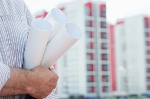 Un obrero de la construcción sosteniendo en sus manos planos —  Fotos de Stock