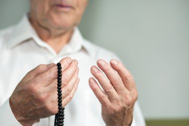Tespih tutan bir yaşlı adamın dua eden eller