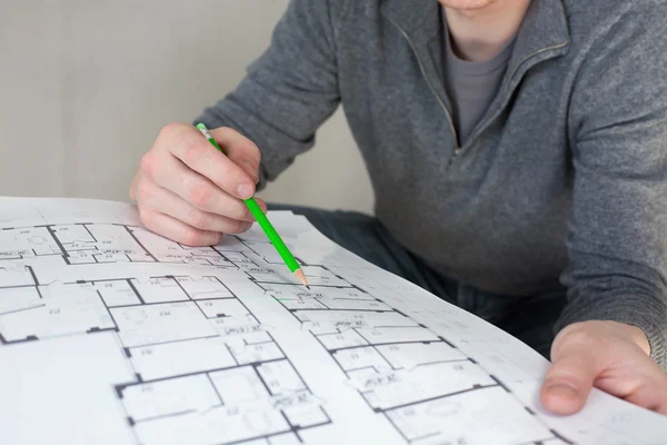Un obrero de la construcción revisando documentos con lápiz en la mano —  Fotos de Stock