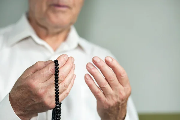 Biddende handen van een oude man met rozenkrans kralen — Stockfoto