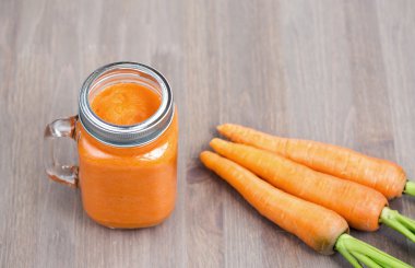 Sağlıklı havuç güler yüzlü bir kavanoza tüp ahşap arka plan