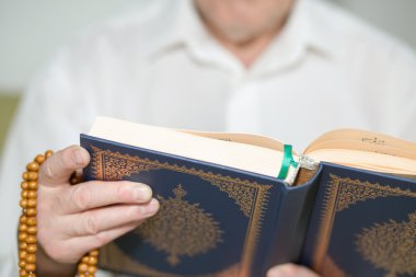 Yaşlı bir adam Kur'an tutan eller. Seçici odak