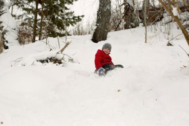 Rüzgârla oluşan kar yığını içinde kışın oynarken mutlu çocuk