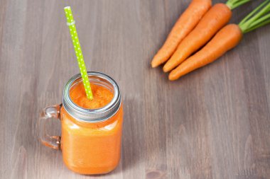 Sağlıklı havuç güler yüzlü bir kavanoza tüp ahşap arka plan