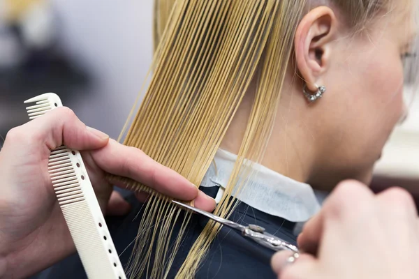 Una peluquera haciendo corte de pelo para una clienta rubia — Foto de Stock
