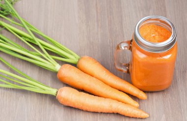 Sağlıklı havuç güler yüzlü bir kavanoza tüp ahşap arka plan