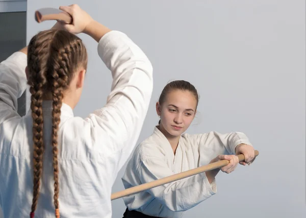 Duas meninas praticar espada no treinamento Aikido no fundo branco — Fotografia de Stock