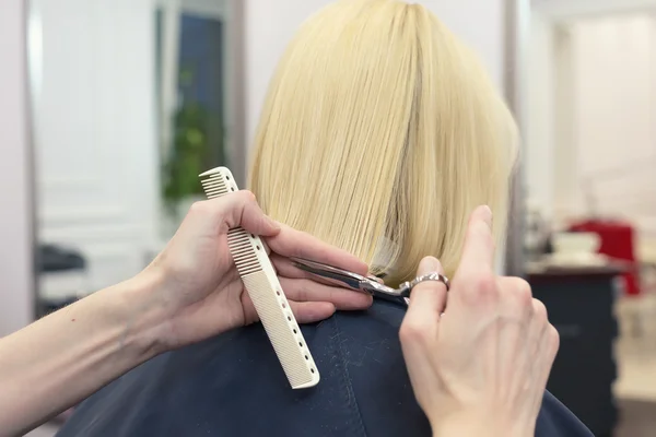 Una peluquera haciendo corte de pelo para una clienta rubia — Foto de Stock