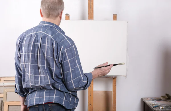 Un artista en estudio pensando delante de un lienzo blanco — Foto de Stock