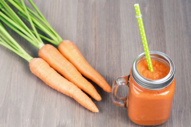 Tüp ahşap arka plan üzerinde bir kavanoza sağlıklı havuç güler yüzlü