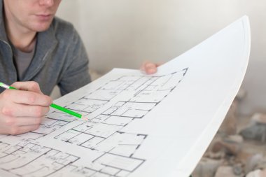 Elinde kalem ile belgelerin incelenmesi bir inşaat işçisi