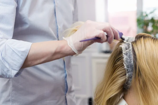 Una peluquera blanqueando el cabello para una clienta rubia — Foto de Stock