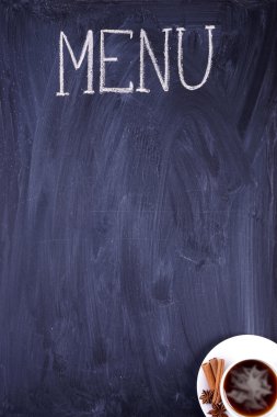 Belgili tanımlık yemek listesi. Tebeşir siyah kirli yazı tahtası üzerinde yazılı. Bir fincan kahve.