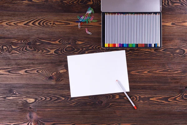Sheet of paper with a pencil on old brown table. — Stock Photo, Image