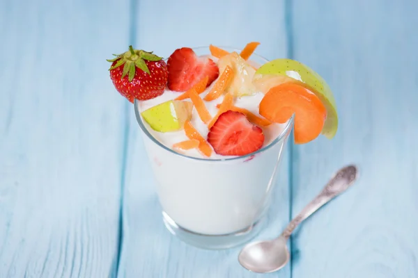 Yoghurt met aardbeien, appels en wortel in een glas. Blauwe achtergrond. — Stockfoto