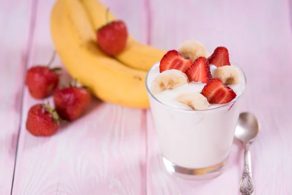 Yoghurt met aardbeien en banaan in een glas. Roze achtergrond. — Stockfoto