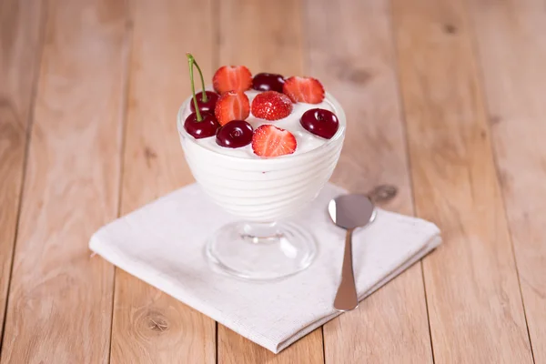 Jogurt z truskawek i wiśni na drewnianym stołem — Zdjęcie stockowe