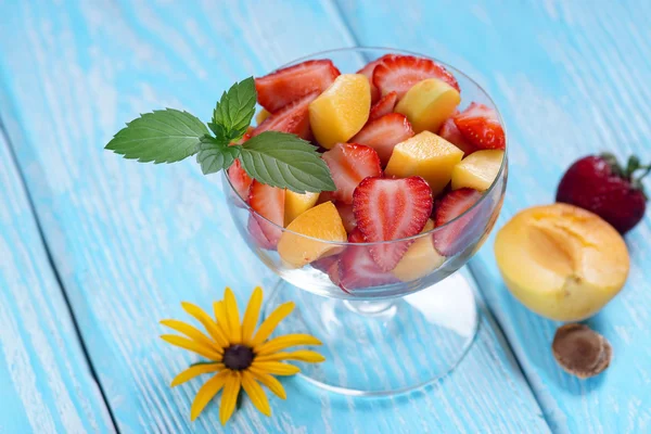 Salade van aardbei en abrikoos met munt laat op een blauwe achtergrond. — Stockfoto