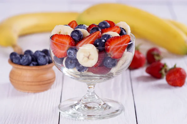 Salade aardbei bananen en bosbessen op de witte tafel. — Stockfoto