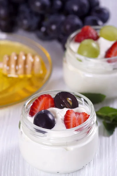 Jogurt z truskawkami i winogron na stole. — Zdjęcie stockowe