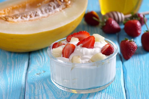 Grecki jogurt z truskawkami i melona na stół niebieski. — Zdjęcie stockowe