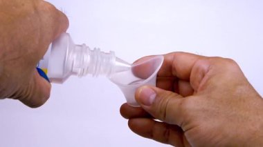 Göz yıkama şişesini ve göz yıkama bardağını iki elinle tut. Sol elinle şişeyi tut ve şişeyi sağ elinle göz yıkama bardağına dök..