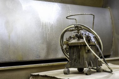 Havalandırma tüpleri ve sprey tabancaya giden boya tankı, boya odasındaki bir masanın üzerine konur..